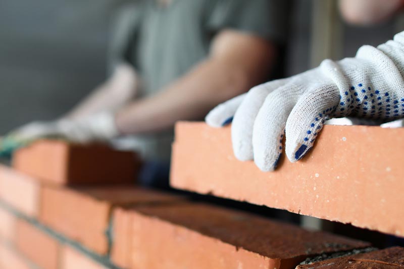 Två arbetare som tillverkar röd tegelvägg på byggarbetsplatsen